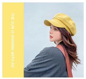 Detail of yellow cotton octagonal newsboy hat with minimalist background on female model
