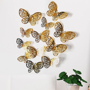 Set of 12 golden hollow butterfly wall stickers displayed on a white wall with plants