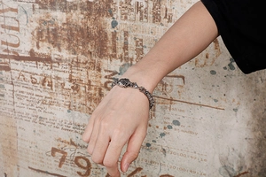 Close-up of vintage silver skull punk bracelet worn on wrist with retro background