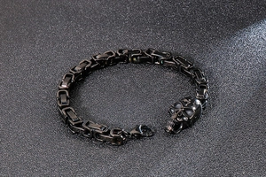 Detail shot of a black skull charm bracelet with gothic steel chain links and lobster clasp