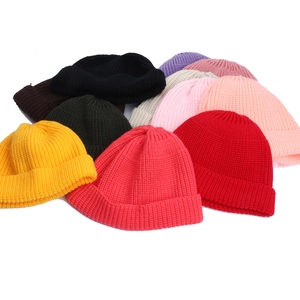 Flat lay of colorful ribbed knit beanies in black, yellow, red, and green tones
