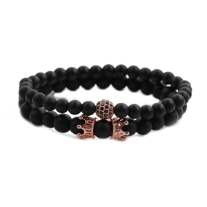 Detail of matte black bead bracelets with rose gold crown and zircon pave ball charms