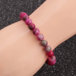 Ethnic style beaded bracelet with natural pink, red and green agate stones on a grey background