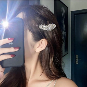 Sparkling rhinestone feather hair clip in silver metal worn by a model in a mirror selfie