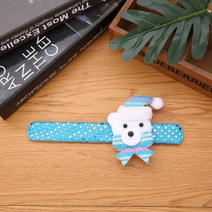 Close-up of blue sequin Christmas slap bracelet with a plush white bear on wooden surface