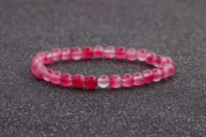Primer plano de pulsera de cuentas de ágata rosa 6mm con piedras traslúcidas sobre negro