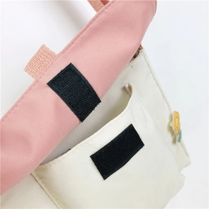 Détail du sac en toile rose avec fermeture velcro noire et petite fleur jaune