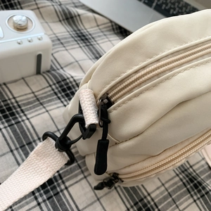 Chic off-white nylon crossbody bag featuring side zipper and metal strap hooks