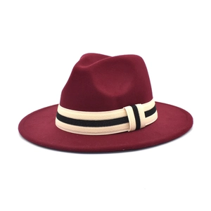 Close-up of wine red wool fedora hat featuring contrast striped band and wide brim