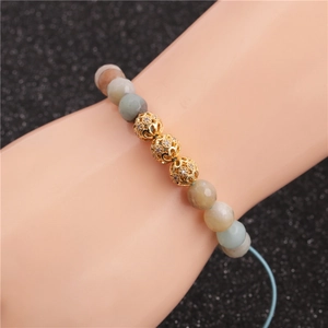 Detail of beaded natural stone bracelet with three gold filigree spheres on a wrist