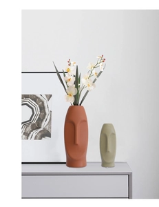 Detail view of abstract face ceramic vases with matte texture in terracotta and grey green