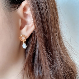 Macro detail of 925 silver flower stud earring with a natural baroque pearl drop