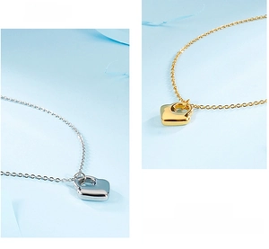 Detail view of heart-shaped lock pendant in gold and silver finishes on a fine link chain