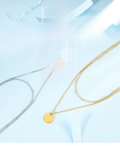 Close-up of double-layered gold and silver necklaces with round polished pendants
