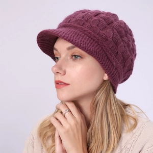 Detalle de gorro con visera de punto trenzado morado y borde acanalado en modelo