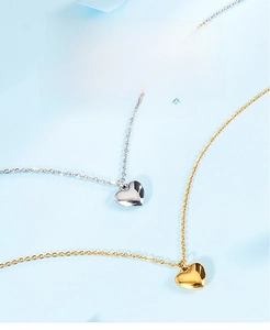 Detail of silver and gold heart pendant necklaces with a polished mirror finish surface