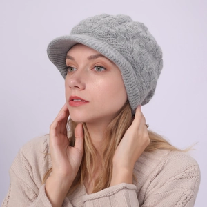 Detalle de gorro de punto gris claro con visera y textura de ochos para invierno cálido