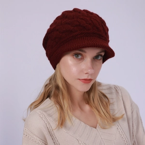 Detalle de gorra de punto trenzado rojo oscuro con visera y textura cálida