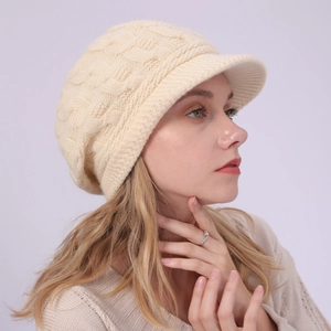 Detalle de gorro de invierno de punto trenzado crema con visera y textura suave de punto