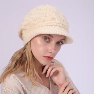 Primer plano del tejido de trenzas y visera de un gorro de punto beige de invierno