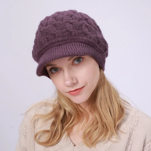 Detalle de gorra de punto morada con tejido trenzado grueso y visera corta para mujer