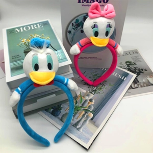 Close-up of plush blue Donald and pink Daisy Duck headbands on a decorative backdrop