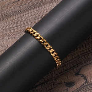 Close-up of a high-polish golden Cuban link chain bracelet on a black display stand