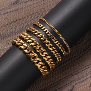 Set of five golden stainless steel Cuban link chains in various widths on a black display