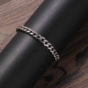 Detailed close-up of a silver stainless steel Cuban link bracelet on a black display stand