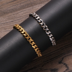 Close-up of gold and silver stainless steel Cuban link chains on a black pedestal
