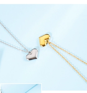Close-up of heart pendant necklaces in gold and silver finish on a light blue background