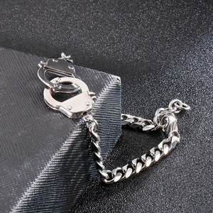 Detail of silver interlocking handcuff charm on a stainless steel Cuban link bracelet