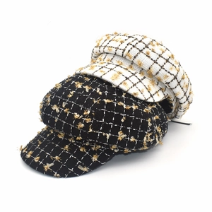 Détail de casquettes newsboy en tweed noir et blanc avec des fils dorés métallisés