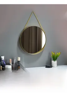 Close-up of a Nordic gold metal round wall mirror hanging with a delicate golden chain