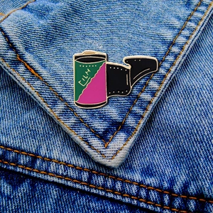 Macro view of vintage film camera roll enamel pin on blue denim fabric texture