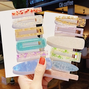 Set of colorful acrylic hair clips with glitter and floral patterns on a card