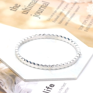 Close-up of a silver geometric wave bangle with cubic zirconia on a marble stand