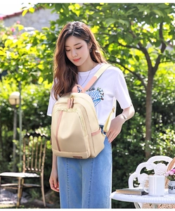 Vista lateral de mochila de nailon beige con correa ajustable y detalles en rosa