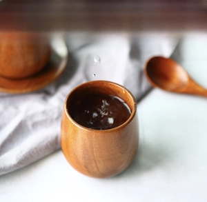 Detailed view of carbonized wood mug with natural grain and coffee pouring in daylight