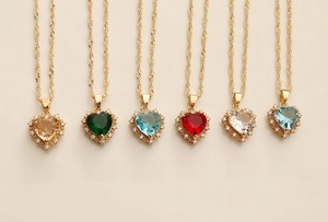 Close-up of heart-shaped zircon pendants in six vibrant colors with gold twisted chains