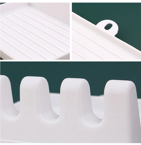 Detail of white kitchen utensil rest showing anti-slip slots and hanging hole