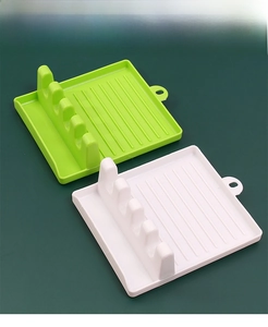 Detail of green and white plastic spatula rest with lid holder and drip tray slots