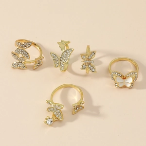 5-piece gold butterfly ring set featuring rhinestones and enamel on a warm beige background