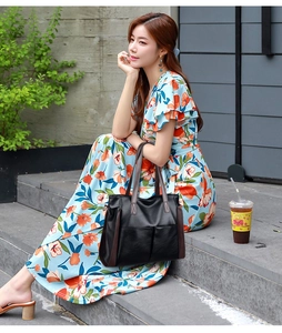 Chic black oversized faux leather tote bag with brown handles in an outdoor setting
