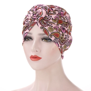 Detail of pink paisley print turban cap with stylish twisted knot design on mannequin