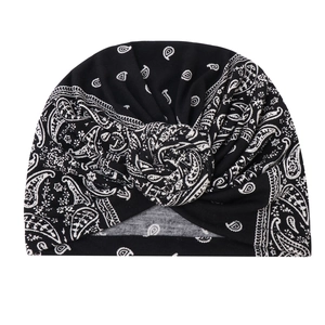 Detail of black turban hat featuring white paisley patterns and a 3D spiral twist knot
