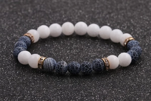 Macro detail of 8mm white stone beads and blue textured beads on a gold-studded bracelet