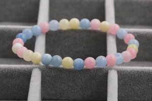 Detail of multi-color morganite beaded bracelet set on a grey jewelry display case