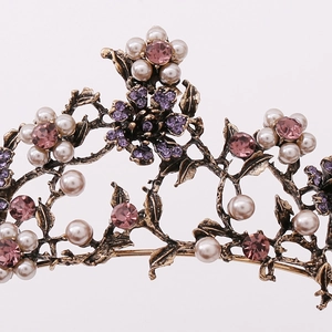 Detailed close-up of baroque crown with white pearls and pink purple crystals