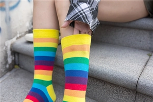 Close-up of vibrant rainbow striped cotton socks worn by a model on outdoor stone steps